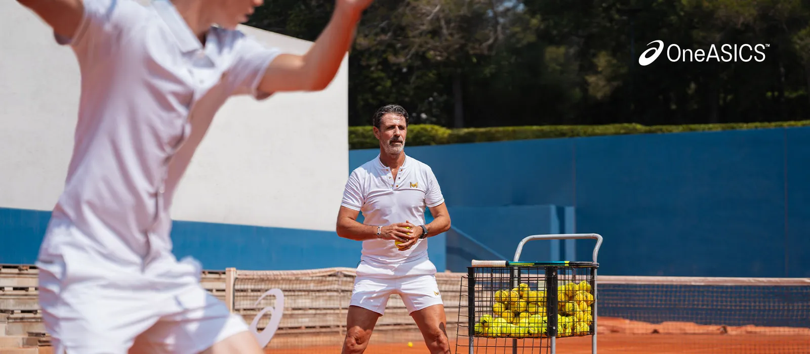 A coach and a tennis player on the court practicing.