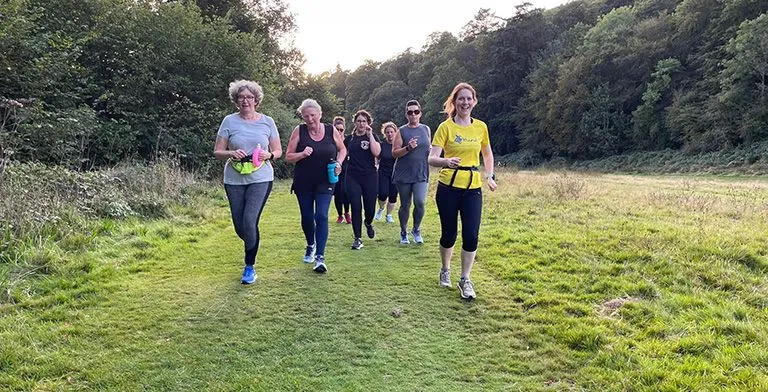 Female runners smiling and running together on grass