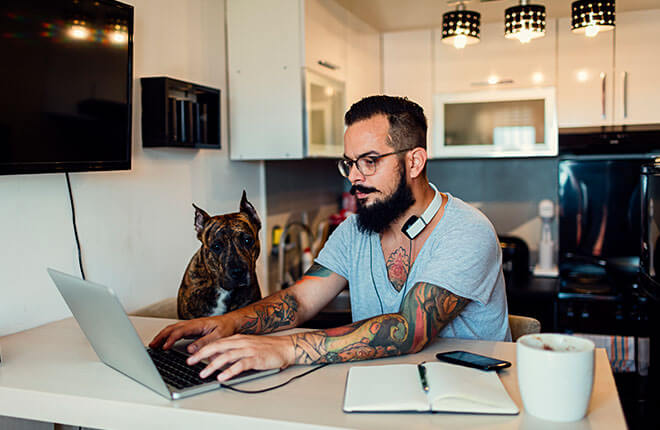 A man sitting at a kitchen counter using a laptop.