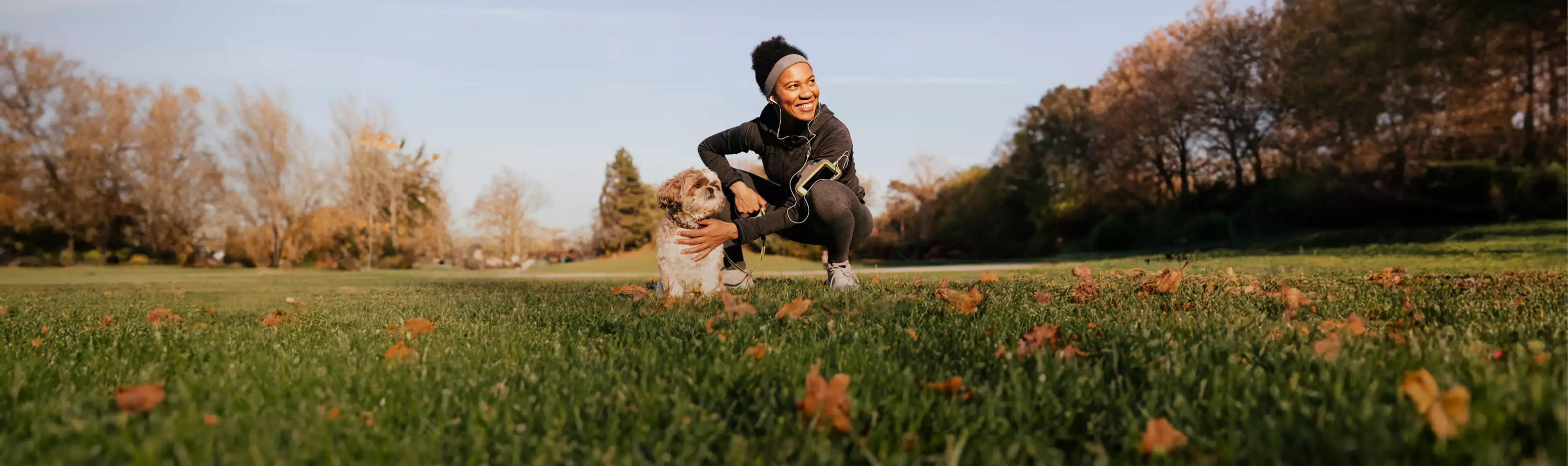 A runner posing with her dog in a field.