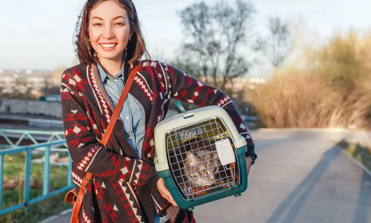 Woman carrying her cat in a cat kennel.