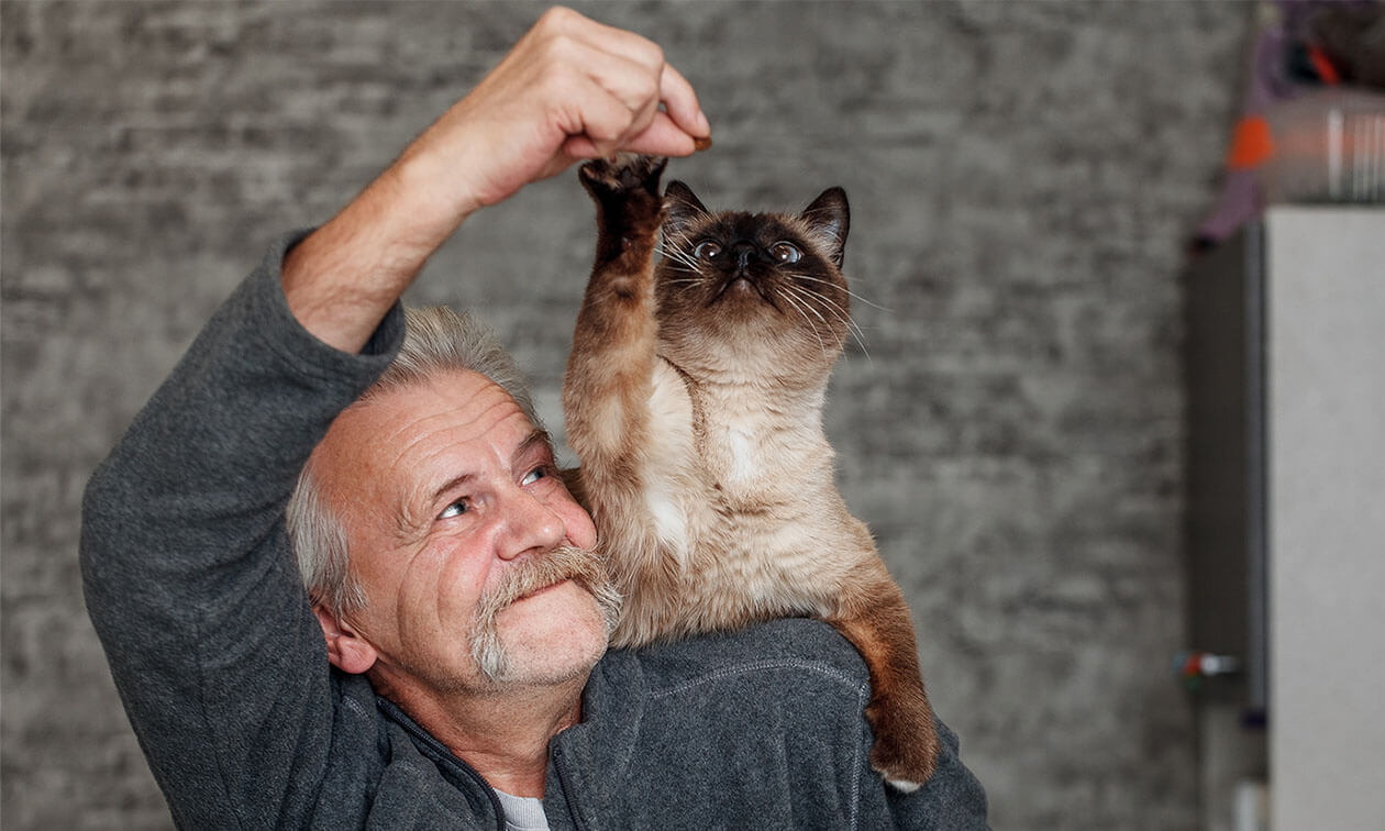 A man with a brown cat on his shoulder.