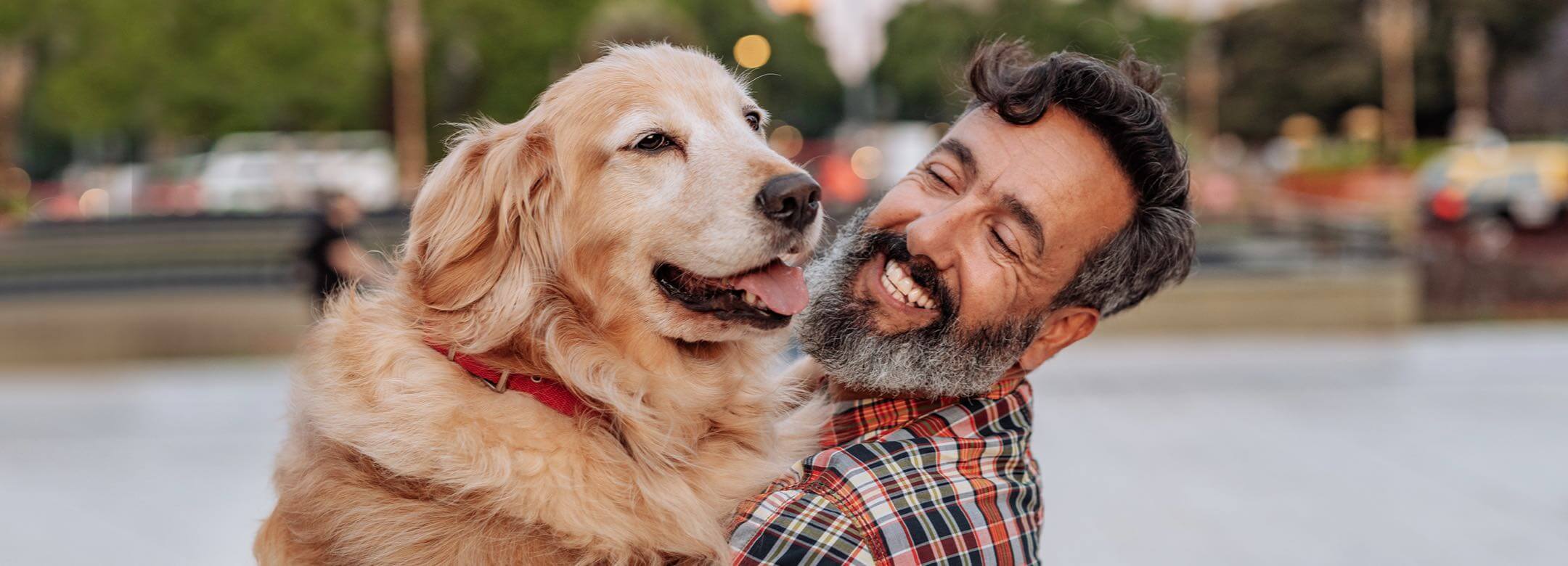 A man with a beard is petting a dog.