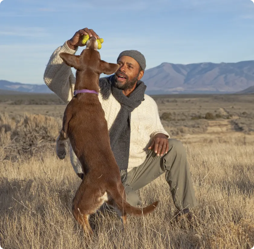 man playing with dog in high desert field