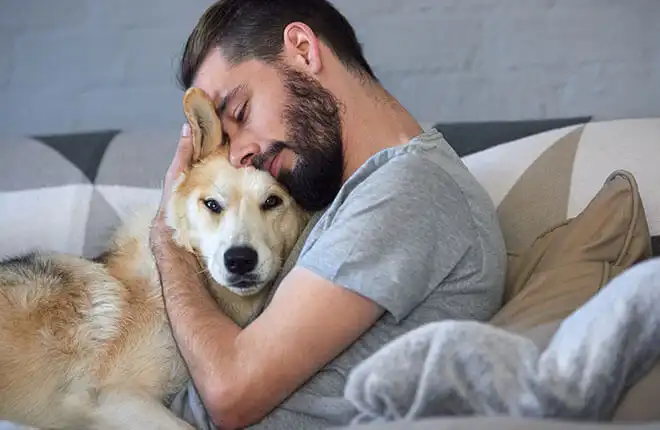 A man sleeping on a couch with his dog.