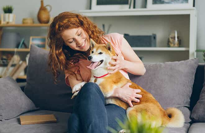 A woman sitting on a couch holding a dog.