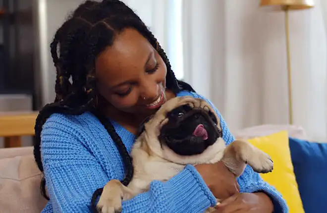 A woman holding a small dog in her arms.