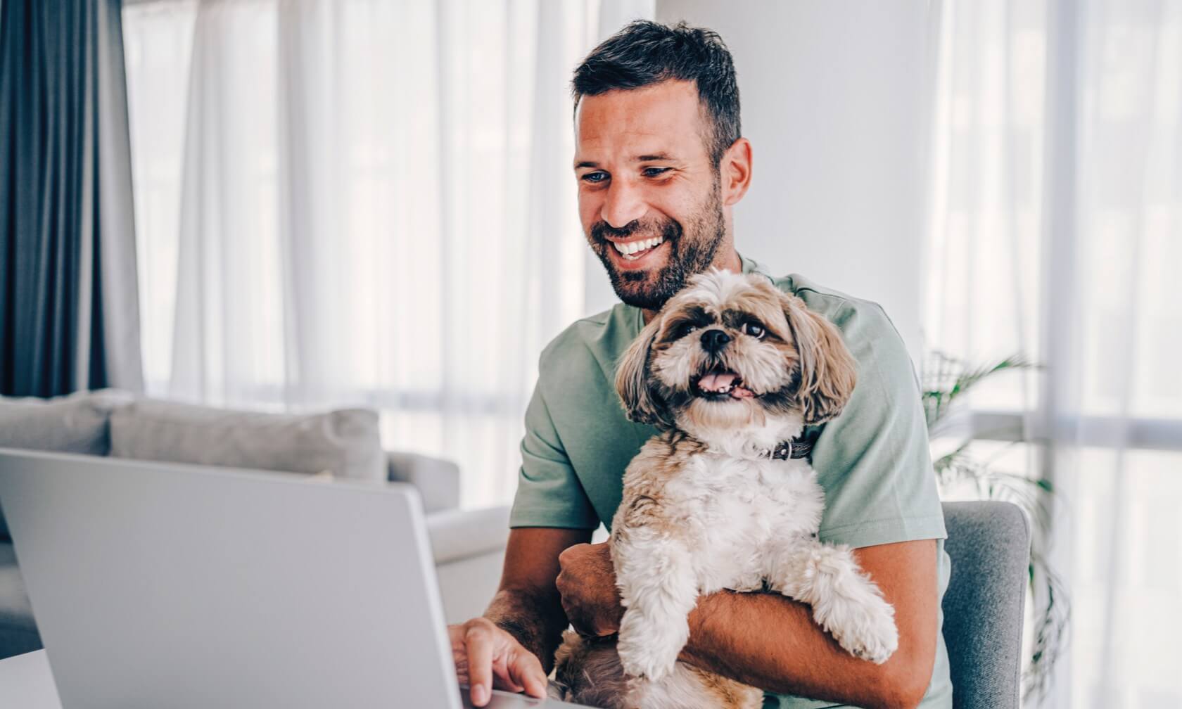 Man holding dog at computer