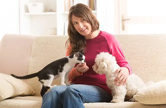 A woman sitting on a couch with two dogs.