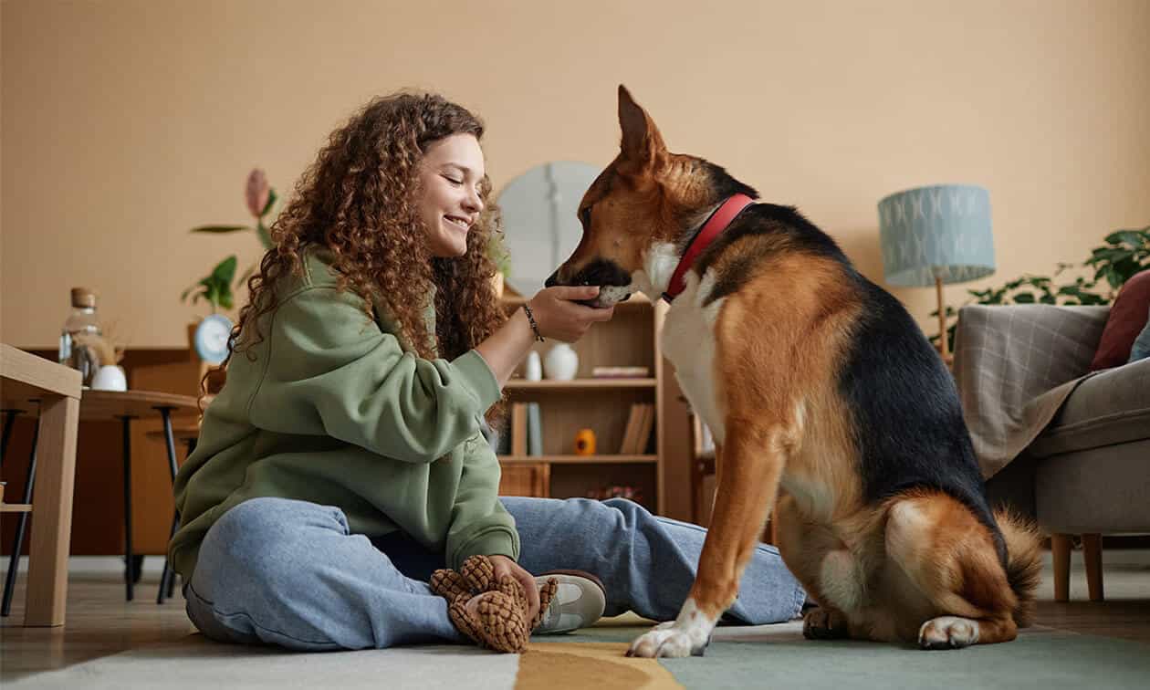 A woman sitting on the floor petting a dog.
