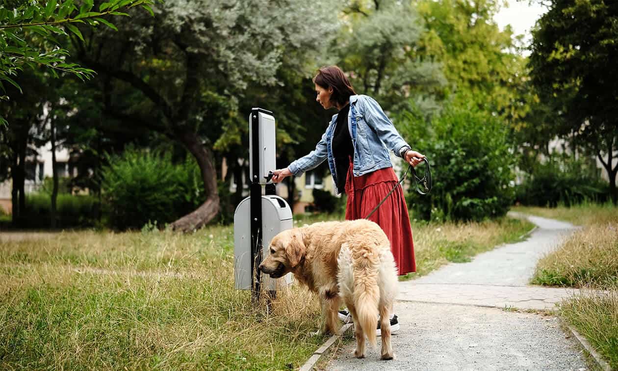 A woman disposing of a poop bag.