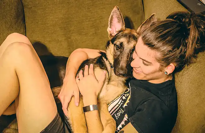 A person laying on a couch with a dog.