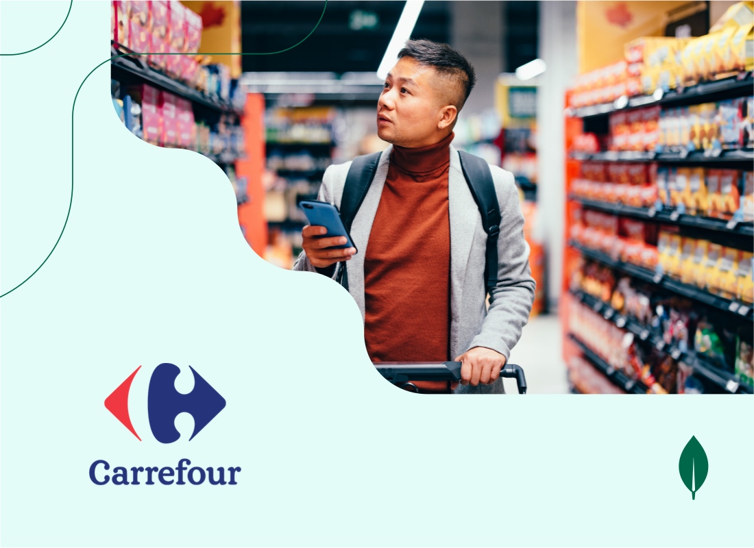  A man in a supermarket checks his phone while standing in front of grocery shelves.