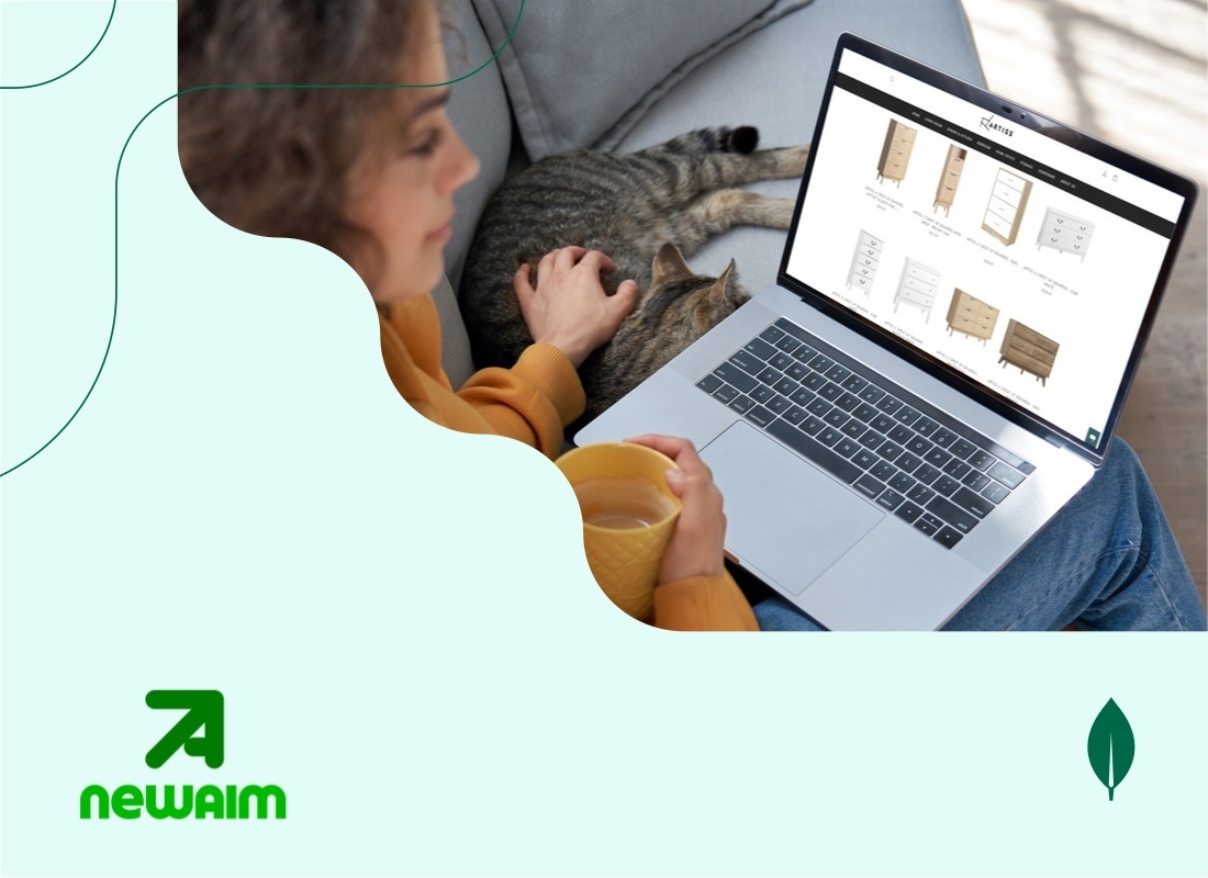 A young woman sitting and browsing an e-commerce website on her laptop, while a cat rests beside the laptop.