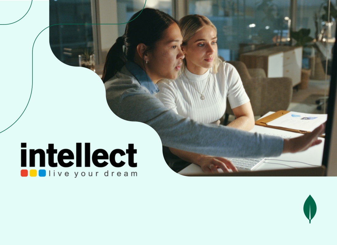 Two young women sitting in an office, looking at a computer and discussing.