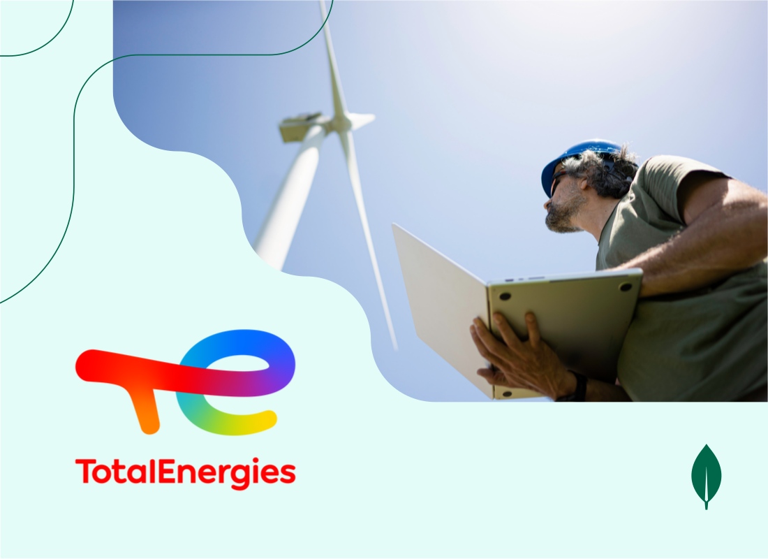 A photo of a company employee near a wind turbine.