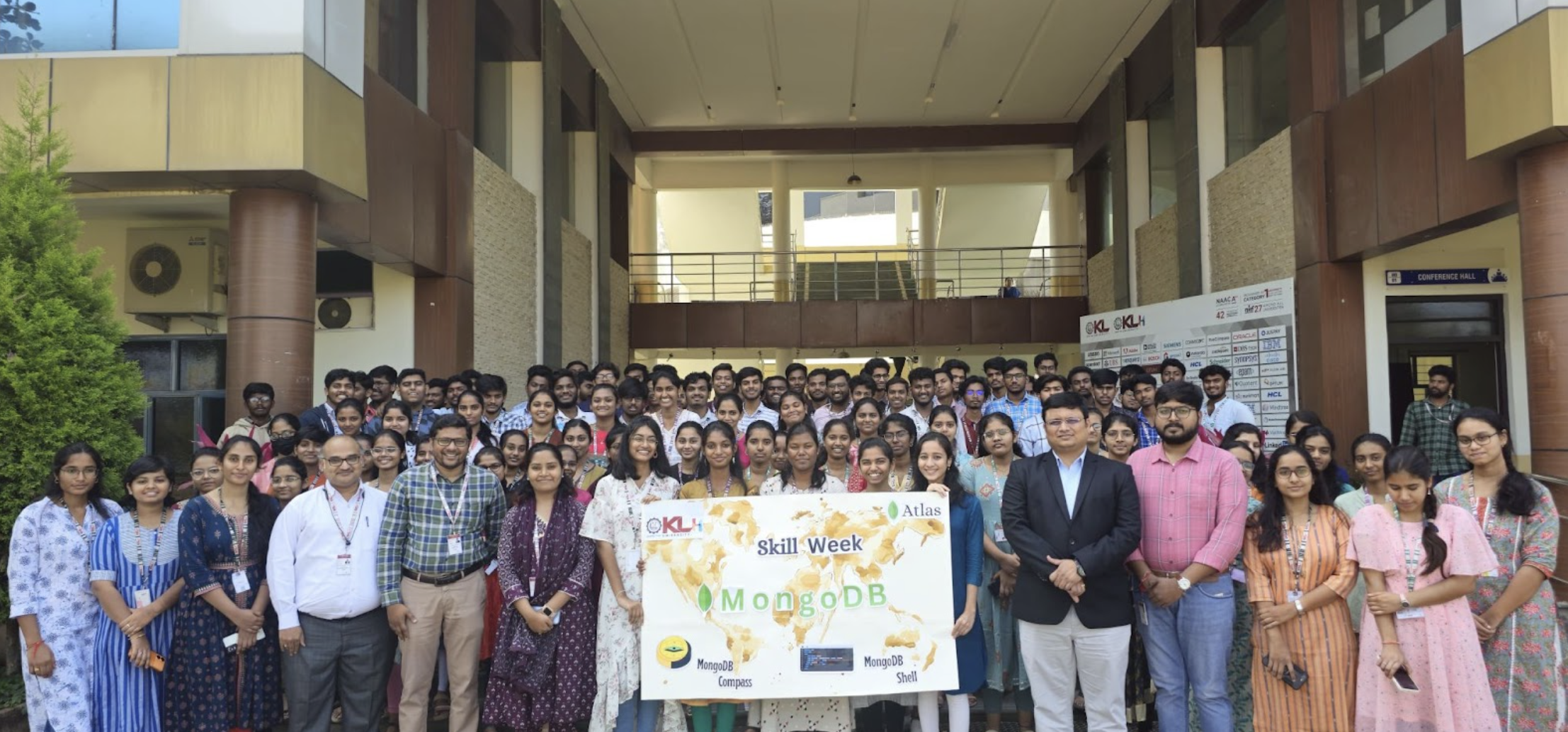 Photo of Chanda in front of the university with other professors and a large group of students.