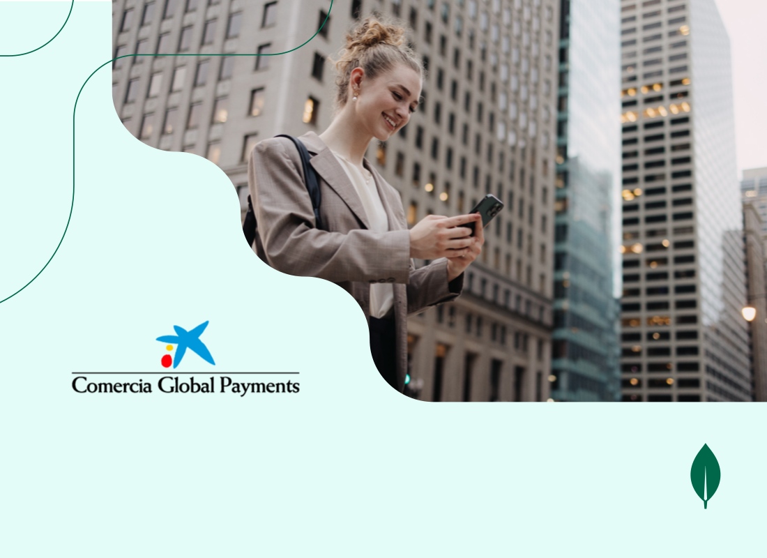 A young woman smiling while looking at her phone, standing in front of tall skyscrapers.