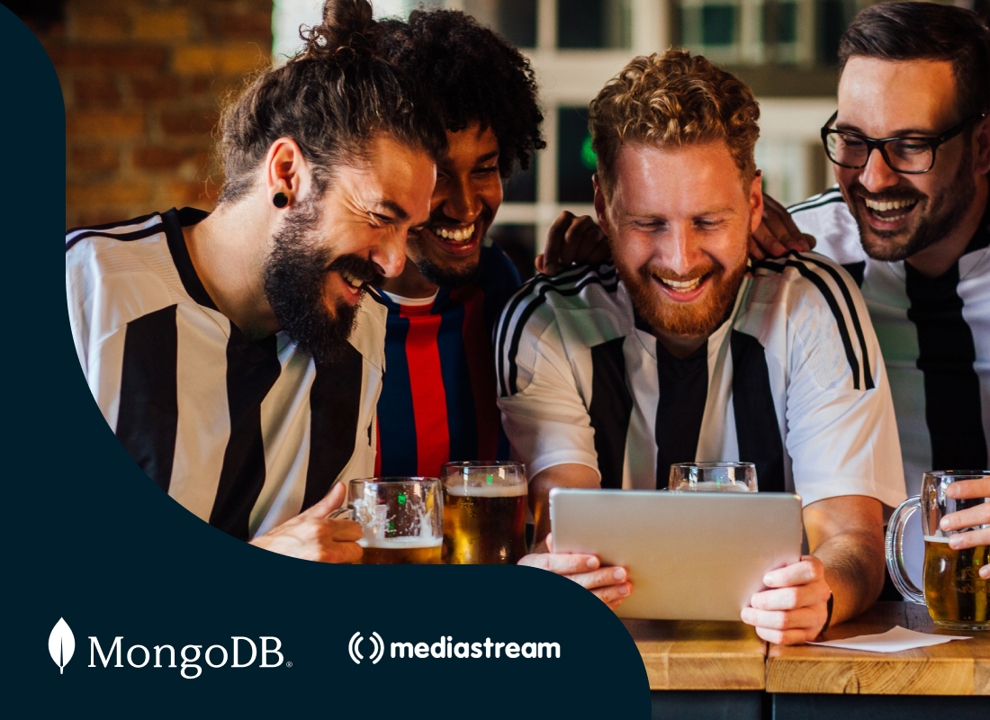 A group of soccer players gathered around an iPad, laughing together.