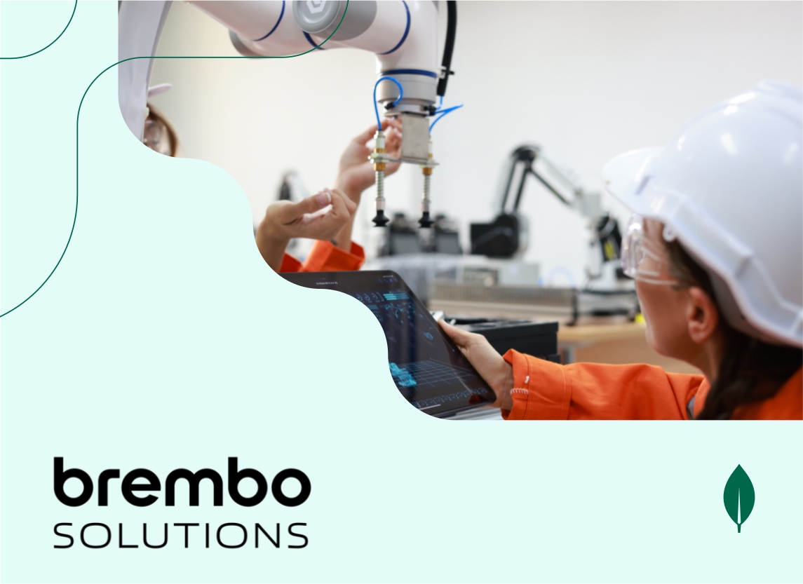 Two women in orange lab coats use a tablet beside an AI instrument.