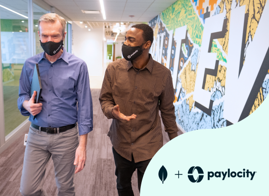 Two professionals engaged in conversation while walking through an office lobby.