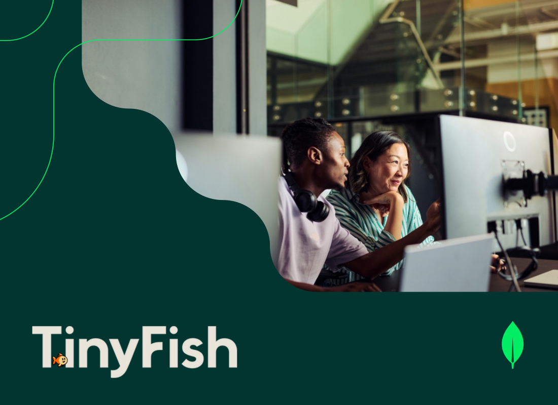 Two professionals sitting in an office, looking at a computer screen and discussing work.