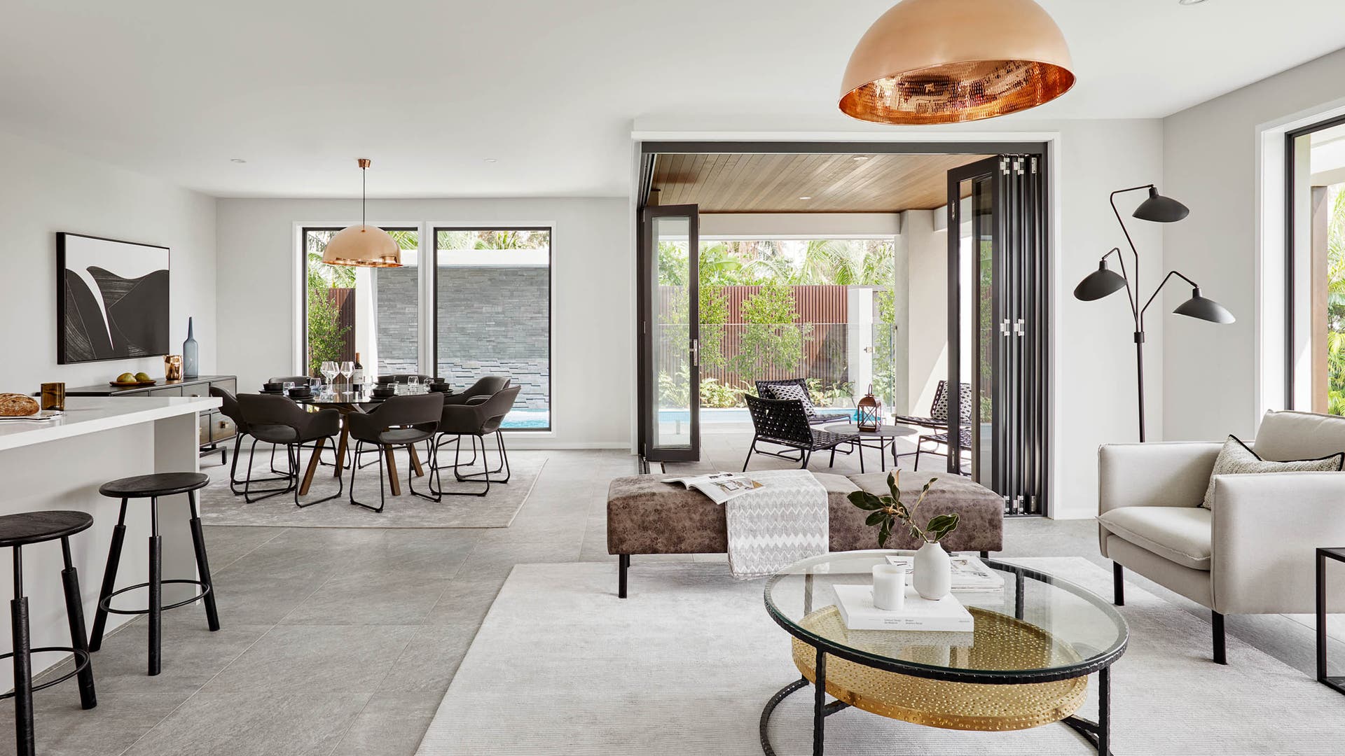 Modern, spacious dining and living area with a tiled floor, large windows, and a cozy terrace featuring comfortable outdoor seating.