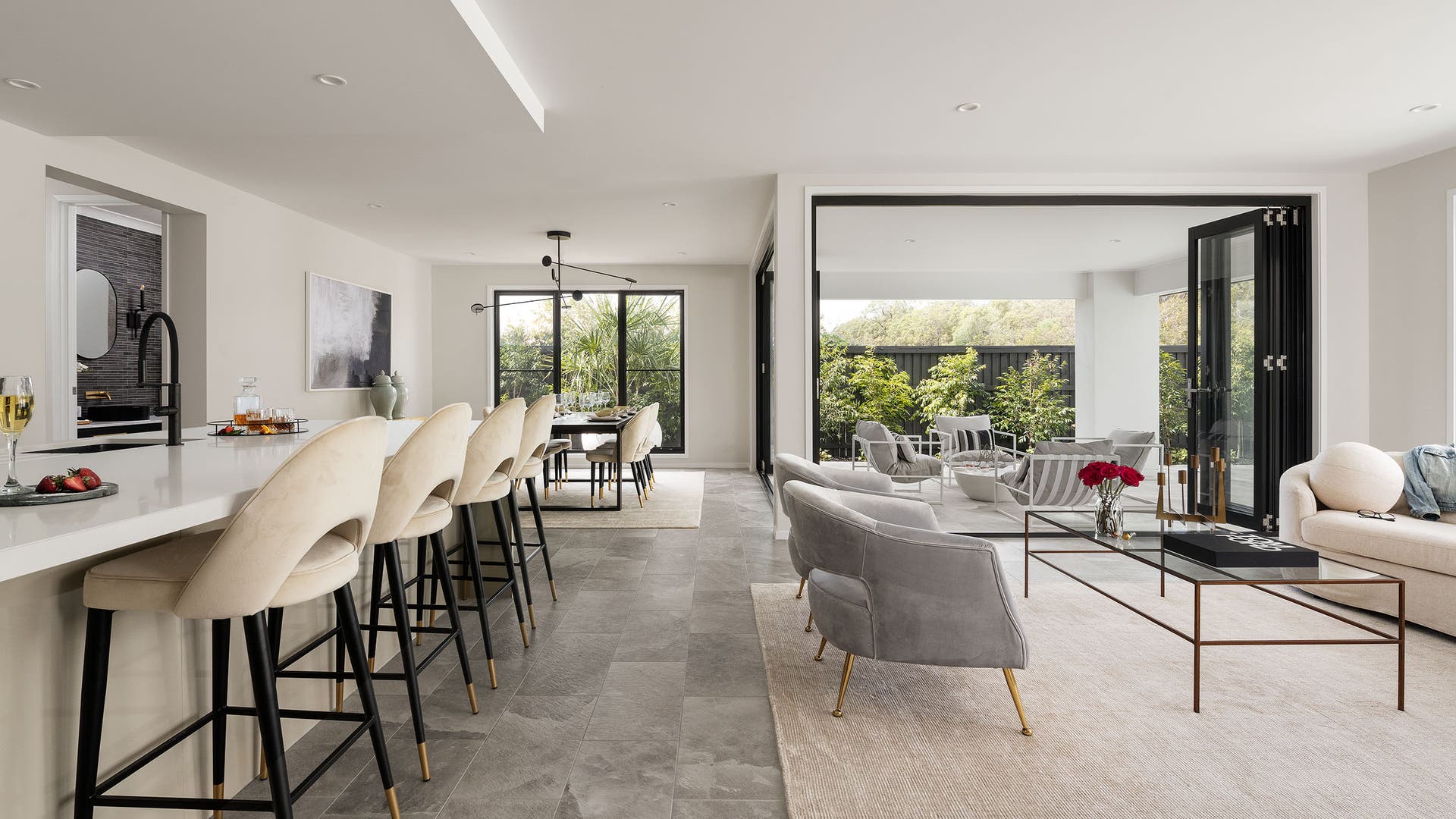 Modern living, dining, and kitchen area with an open-style patio and fully styled landscape.