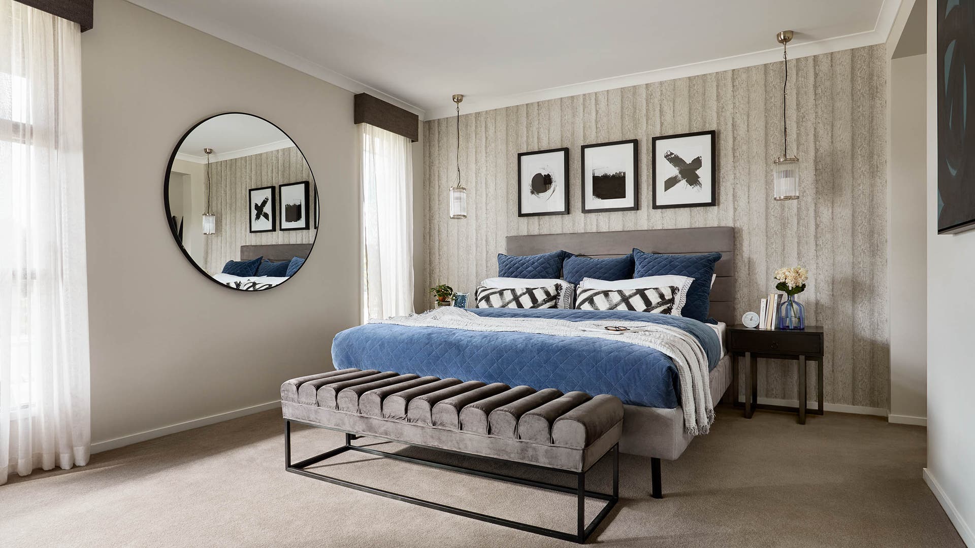 Modern-style bedroom with grey neutral-toned walls, dark blue bed accessories, and black-edged framed decor.