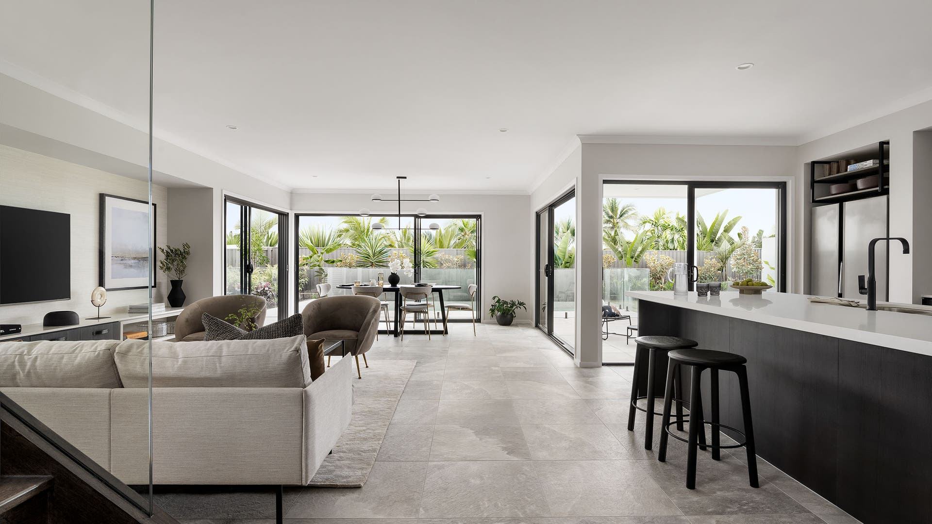 Modern living and kitchen area with floor-to-ceiling windows, tiled floor, and sleek, contemporary design elements