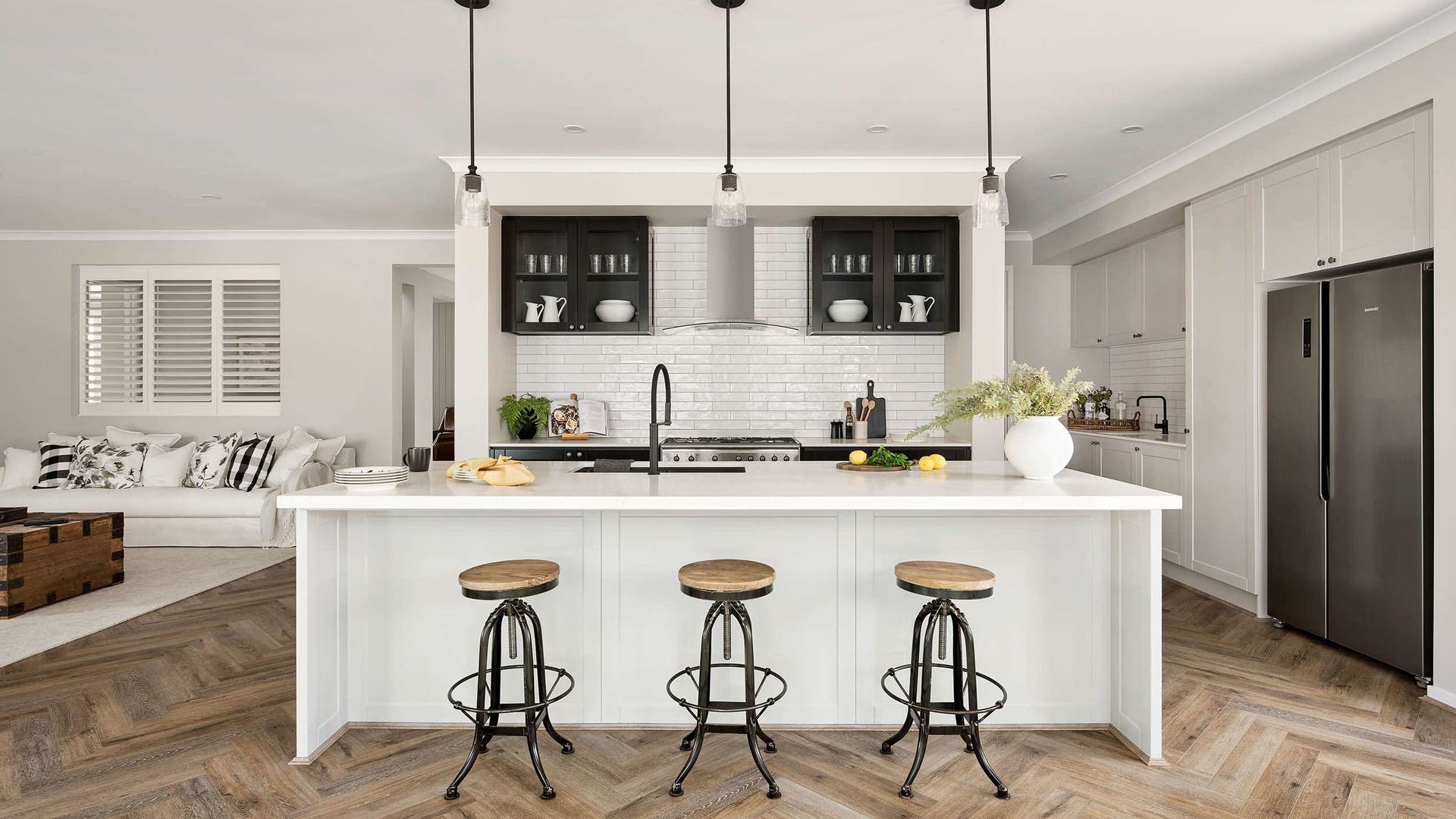 Spacious modern kitchen zone with natural white coloured scheme and dark cabinets.
