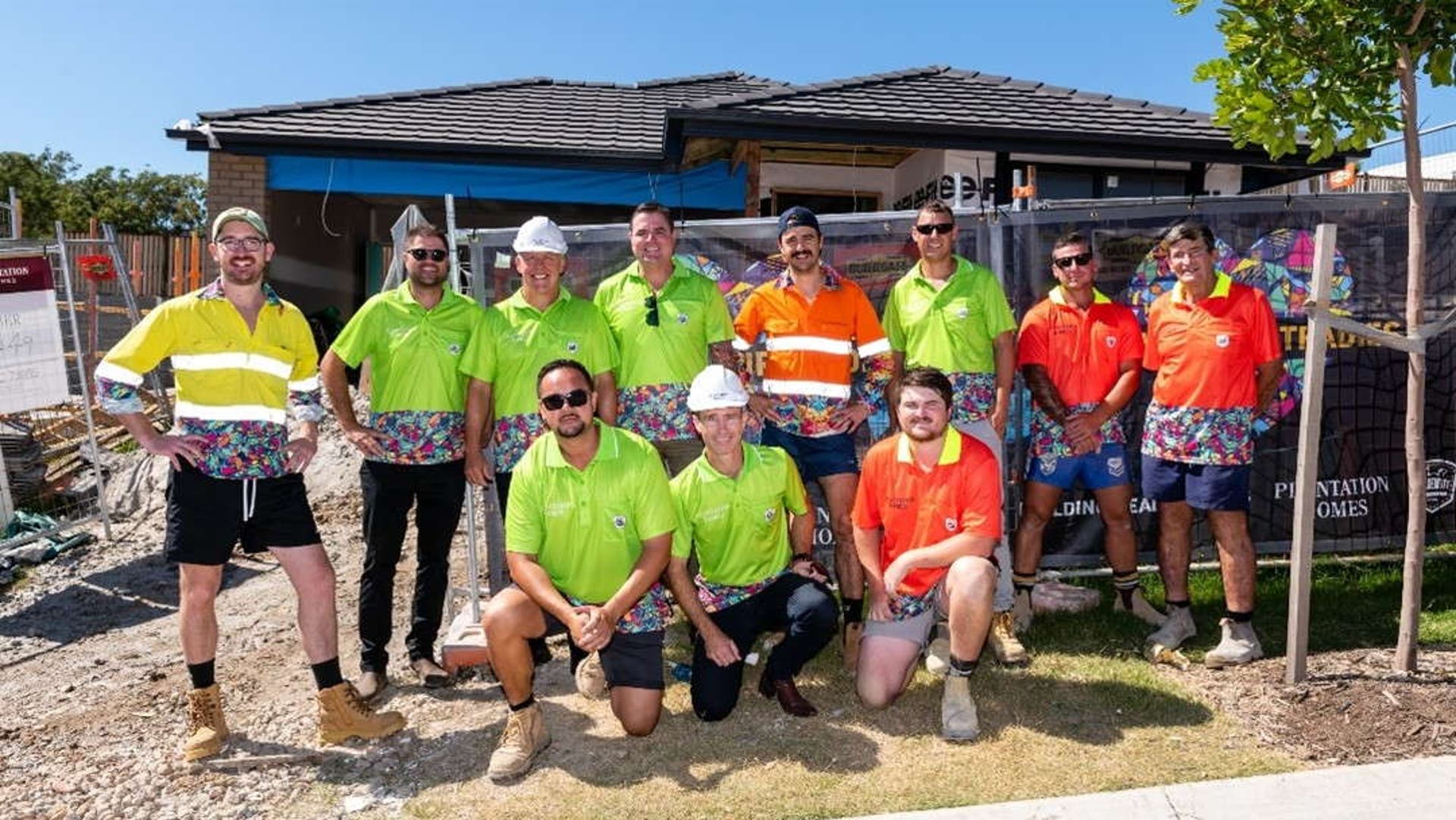 Plantation homes tradies wearing colourful Plantation homes workwear and standing outside of construction site