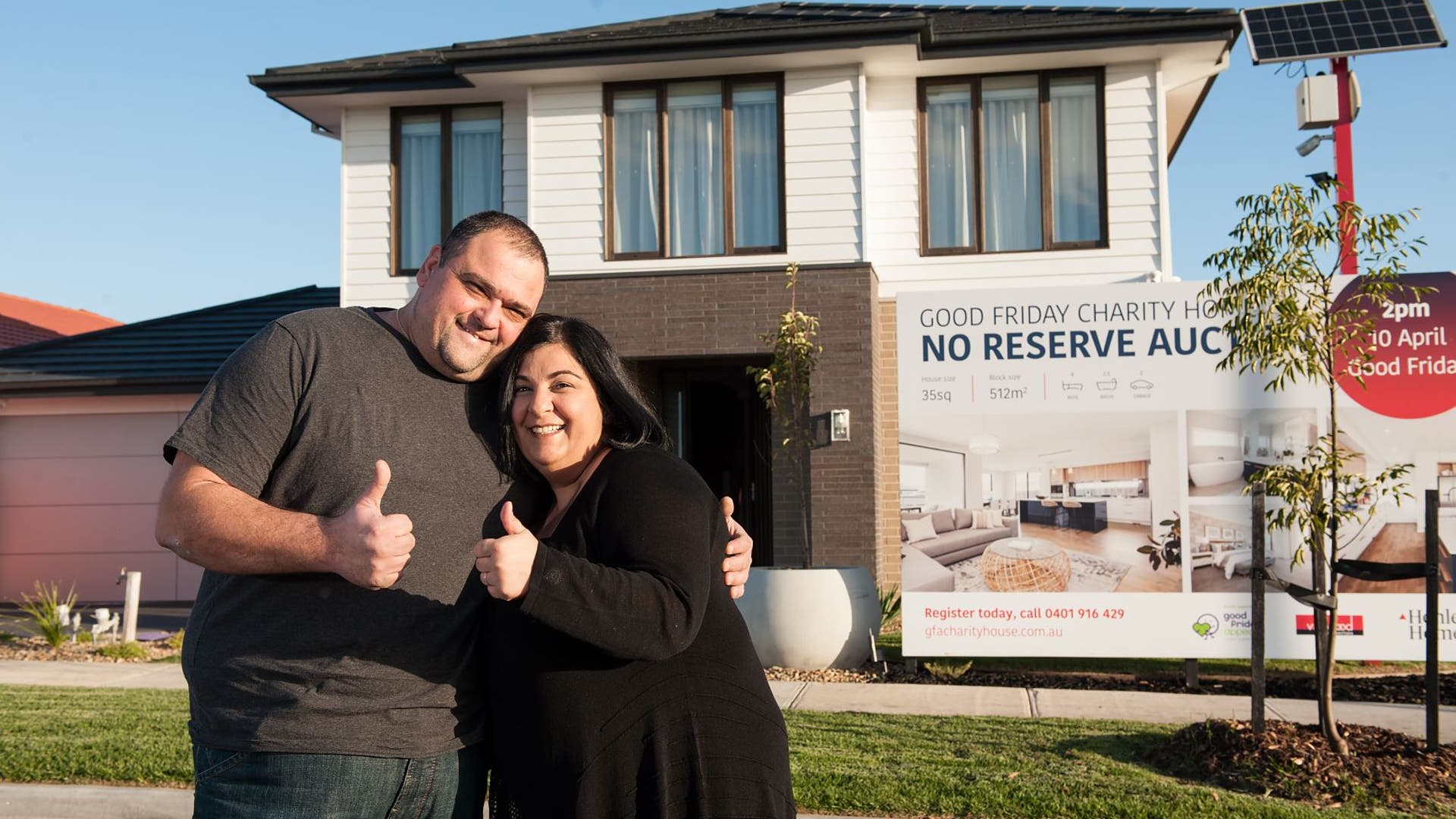 Successful bidders hugging and celebrating securing the 2020 Good Friday Appeal Charity Home standing in front of the double storey home.