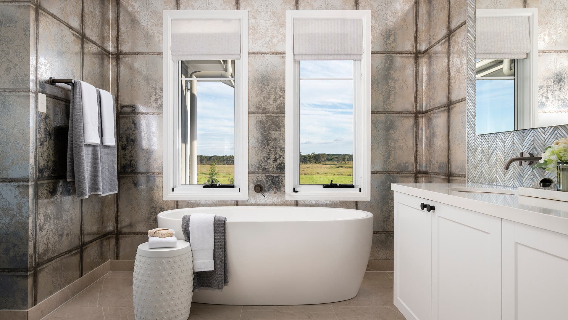 Modern bathroom area with big windows and a bronze accent tiled walls.