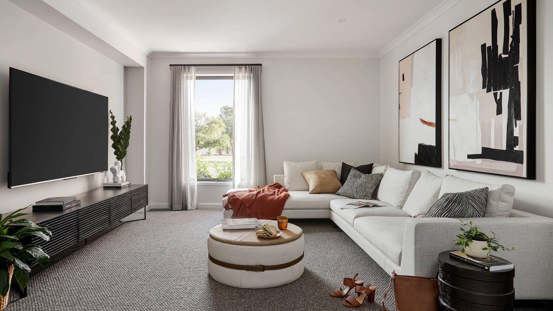 Cosy theatre room featuring a light grey couch with a chase, huge tv and carpet for the flooring.