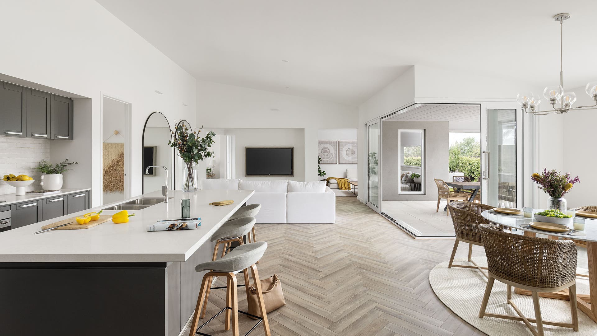 Carmelle 31A kitchen, living, dining and alfresco area on display in Kalkallo. Featuring an open plan zone with crisp whites and light oak herringbone timber flooring.