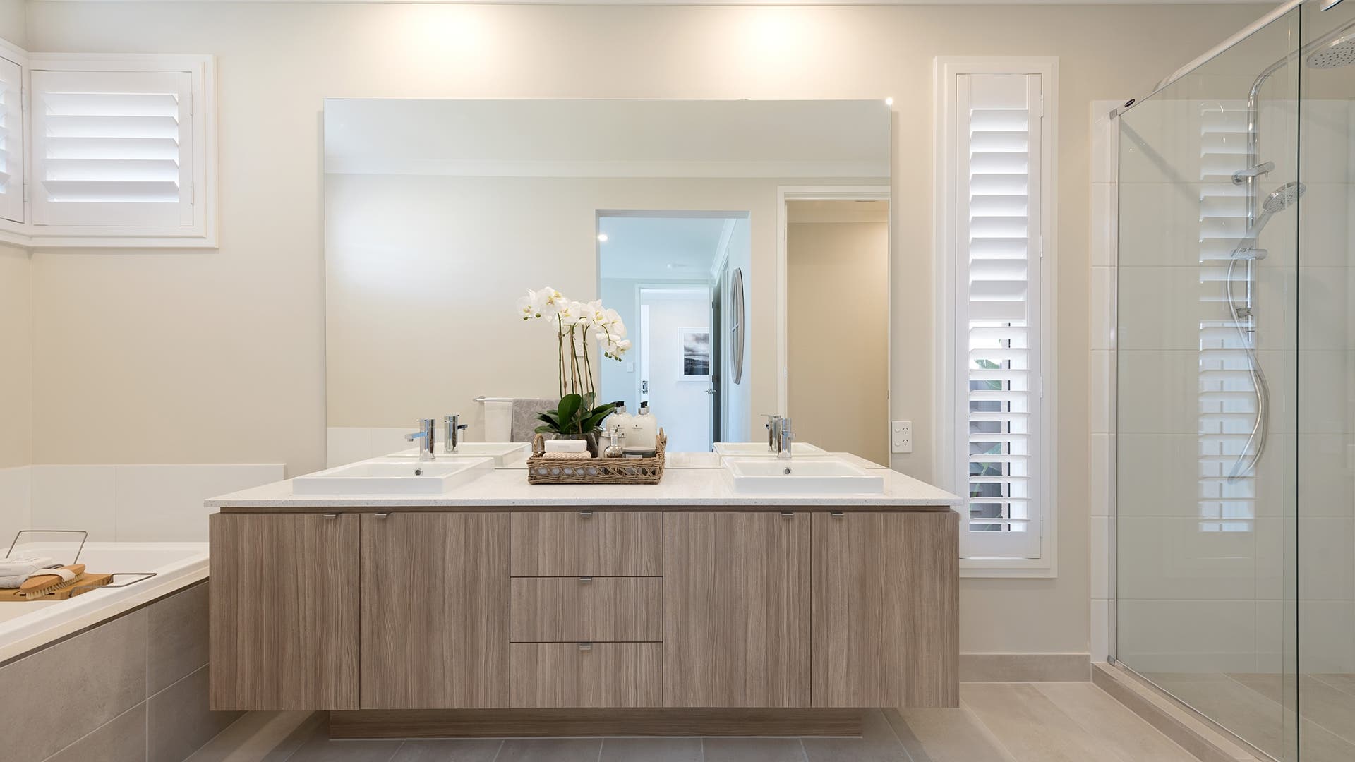 Modern neutral warm toned bathroom with stone bench and Plantation shutters