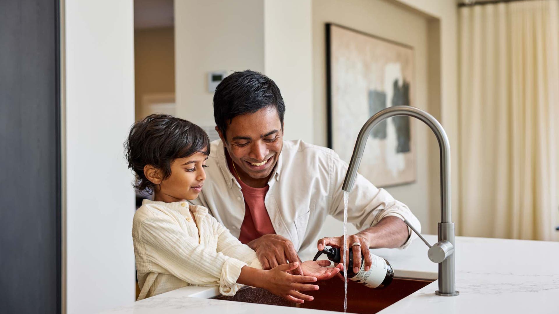 father and child washing hands in the kitchen