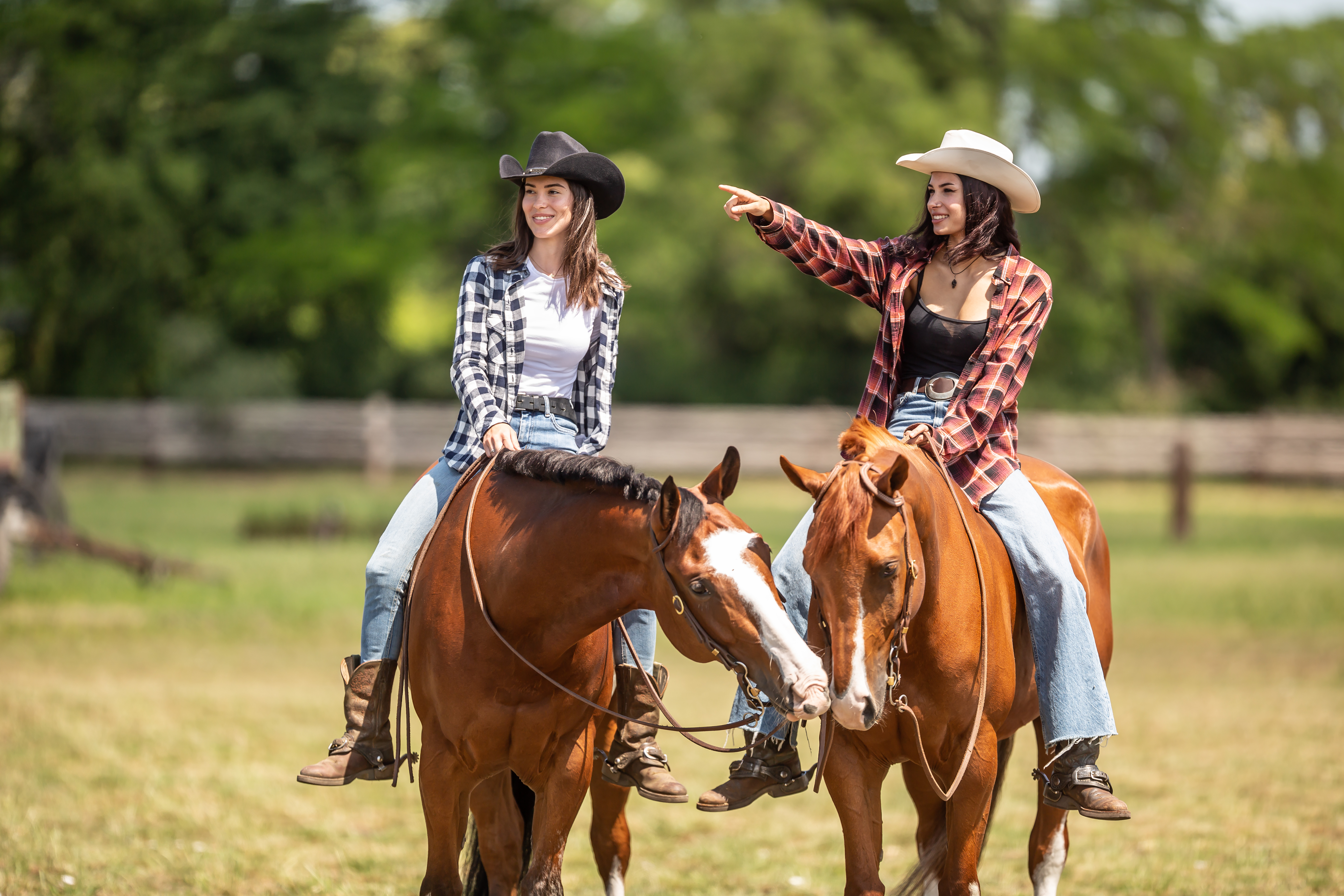 Two_women_on_horses_wearing_cowboy_hats_boots_and_plaid_shirts.jpeg