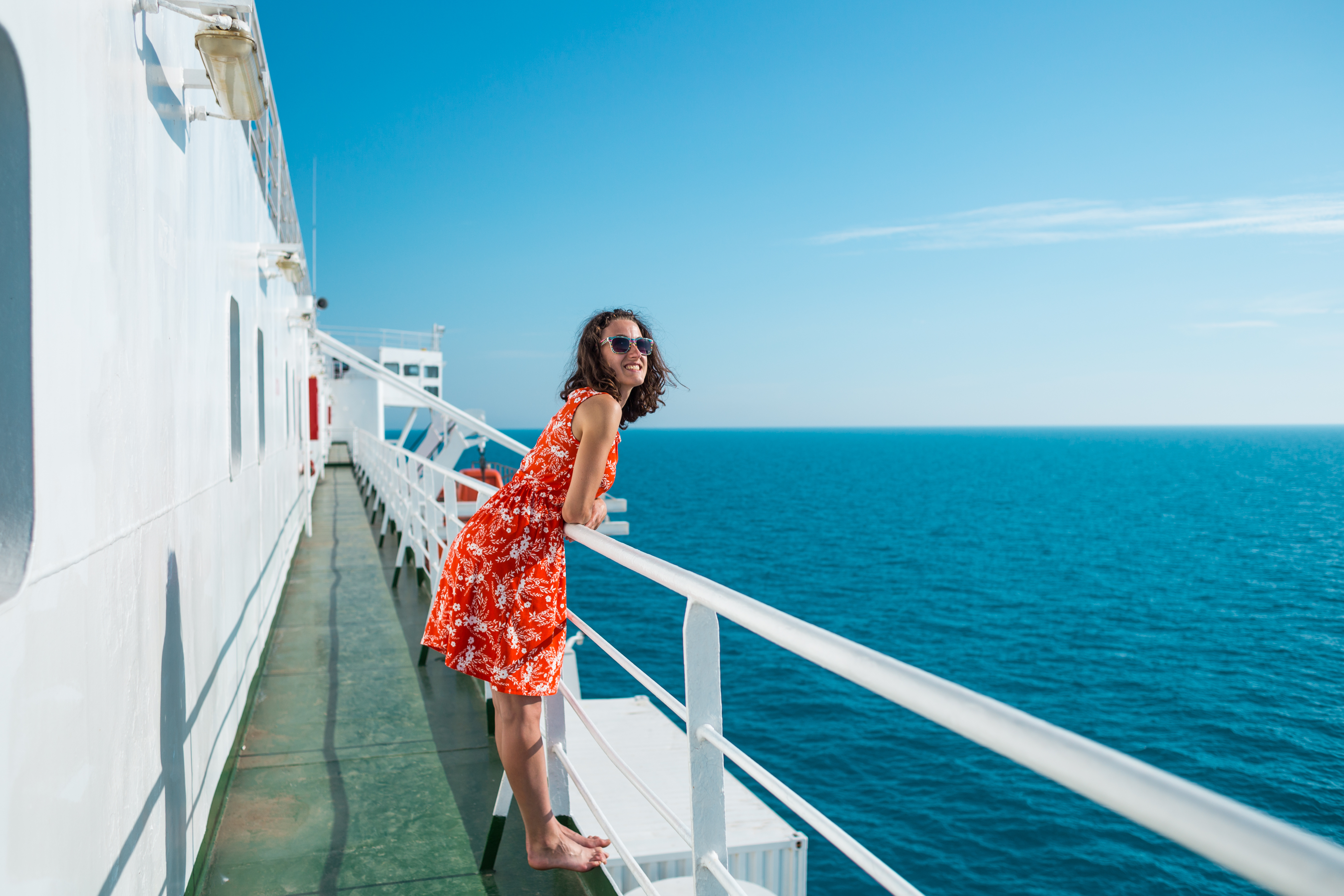 Woman_in_a_red_floral_dress_leaning_on_a_ship_railing.jpeg