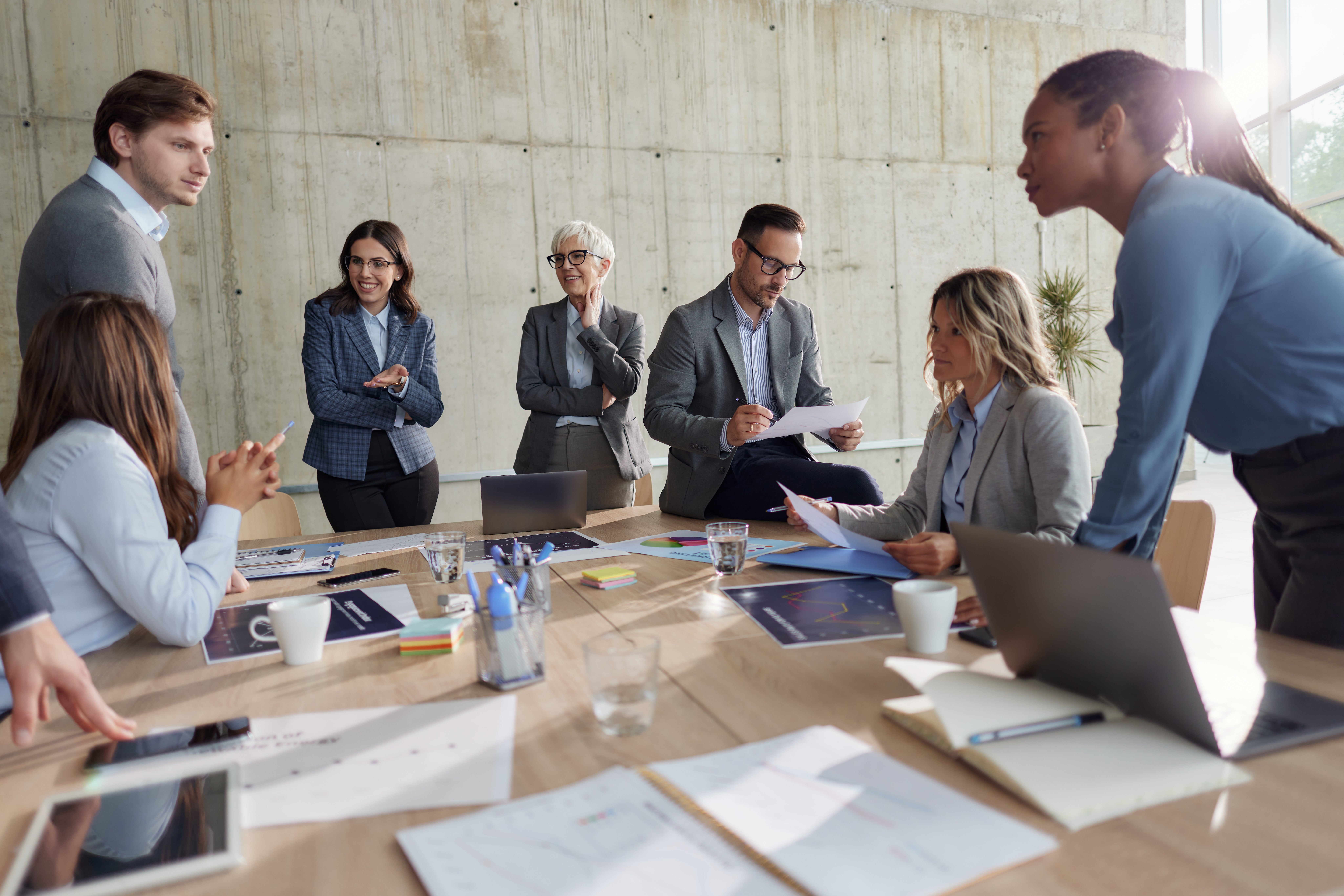 Team of happy entrepreneurs communicating while working with reports on a meeting in the office