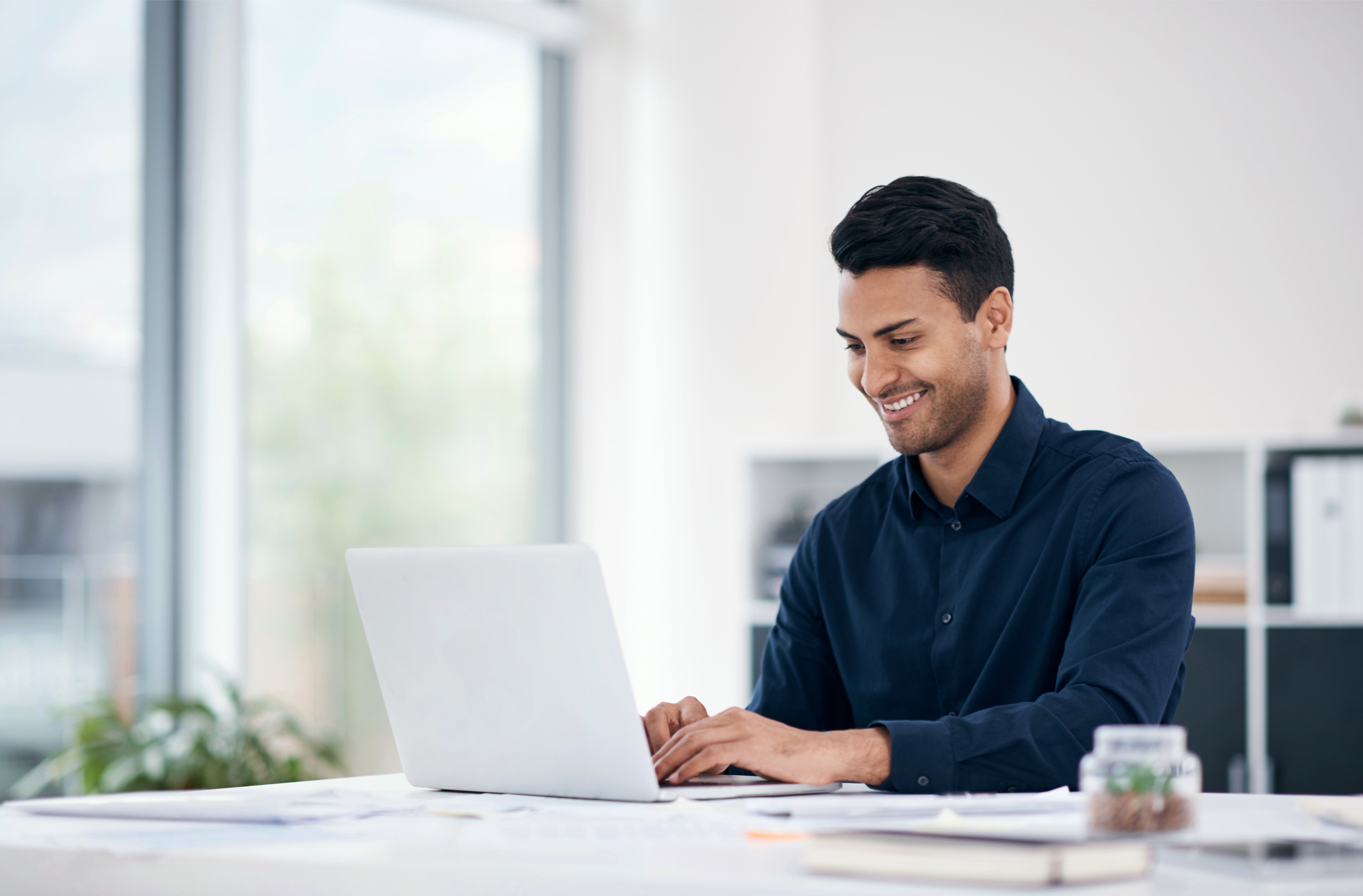 Shot of a young businessman using a laptop at his desk in a modern office