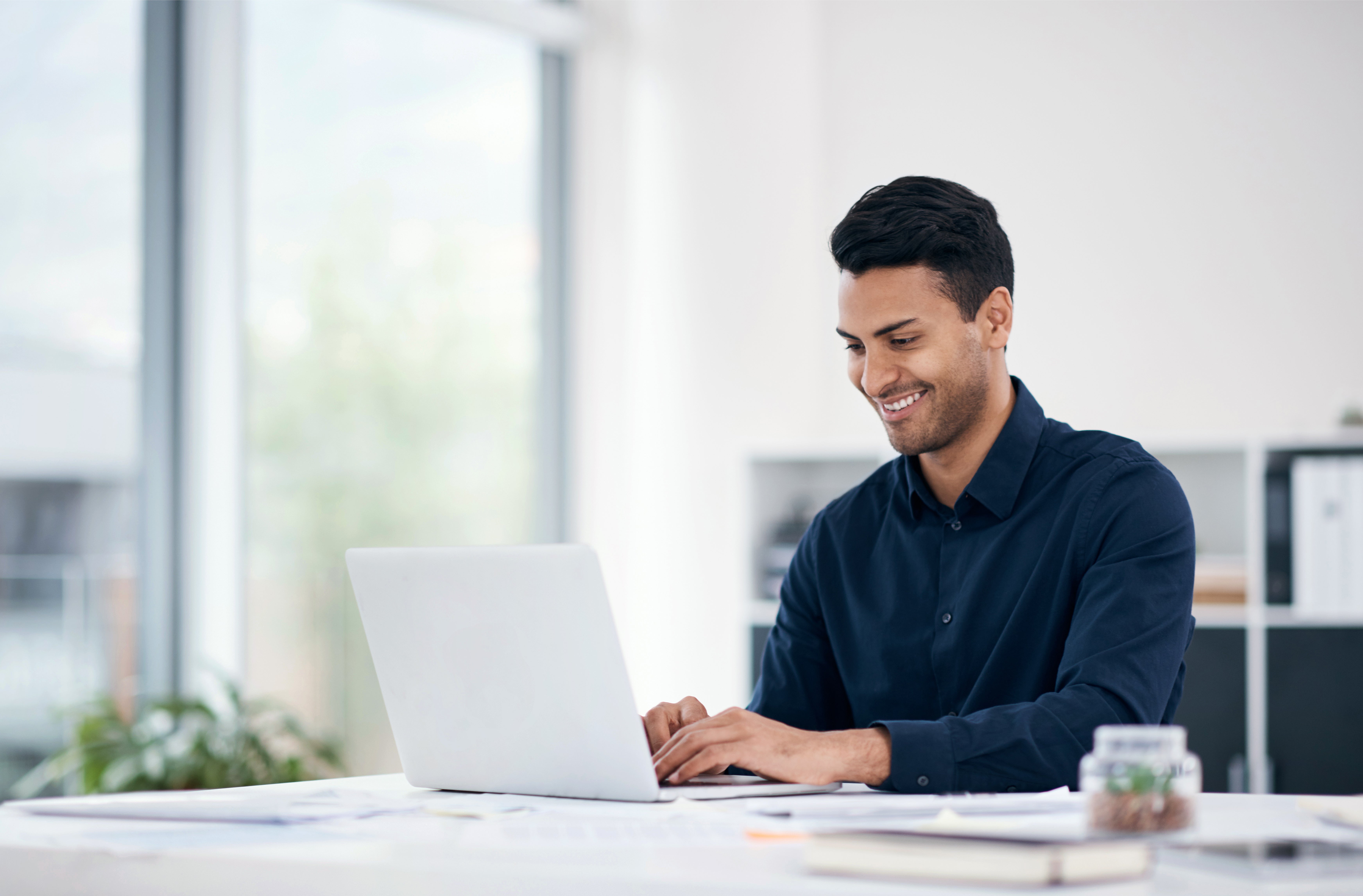 Shot of a young businessman using a laptop at his desk in a modern office