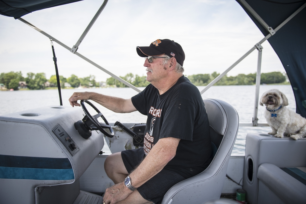 Older man in black shirt and black ballcap piloting a boat