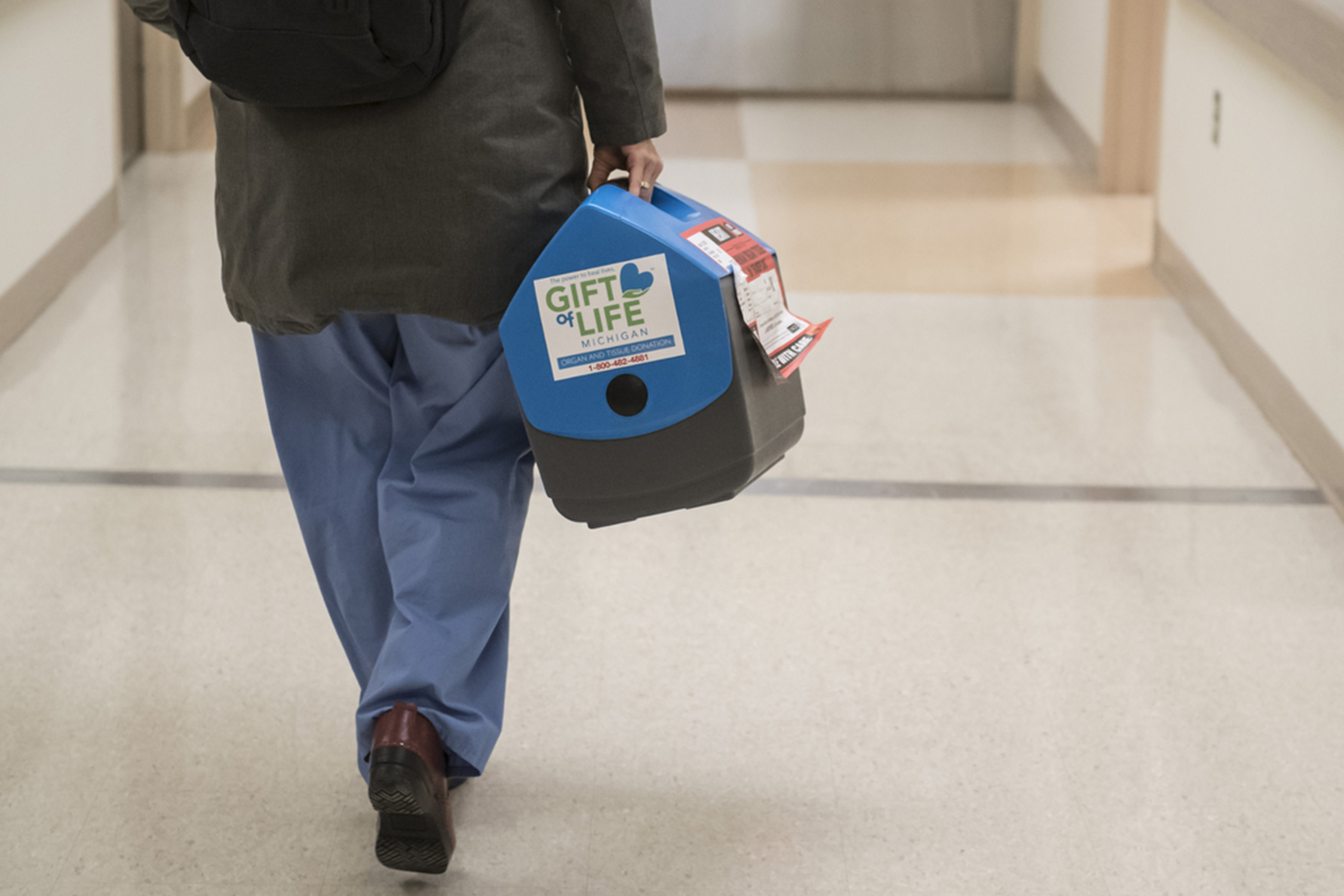 Person walking down a hallway with a cooler.