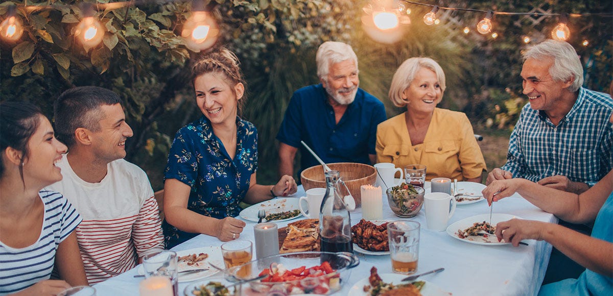 Family members sitting around a table in the garden and having a family reunion party