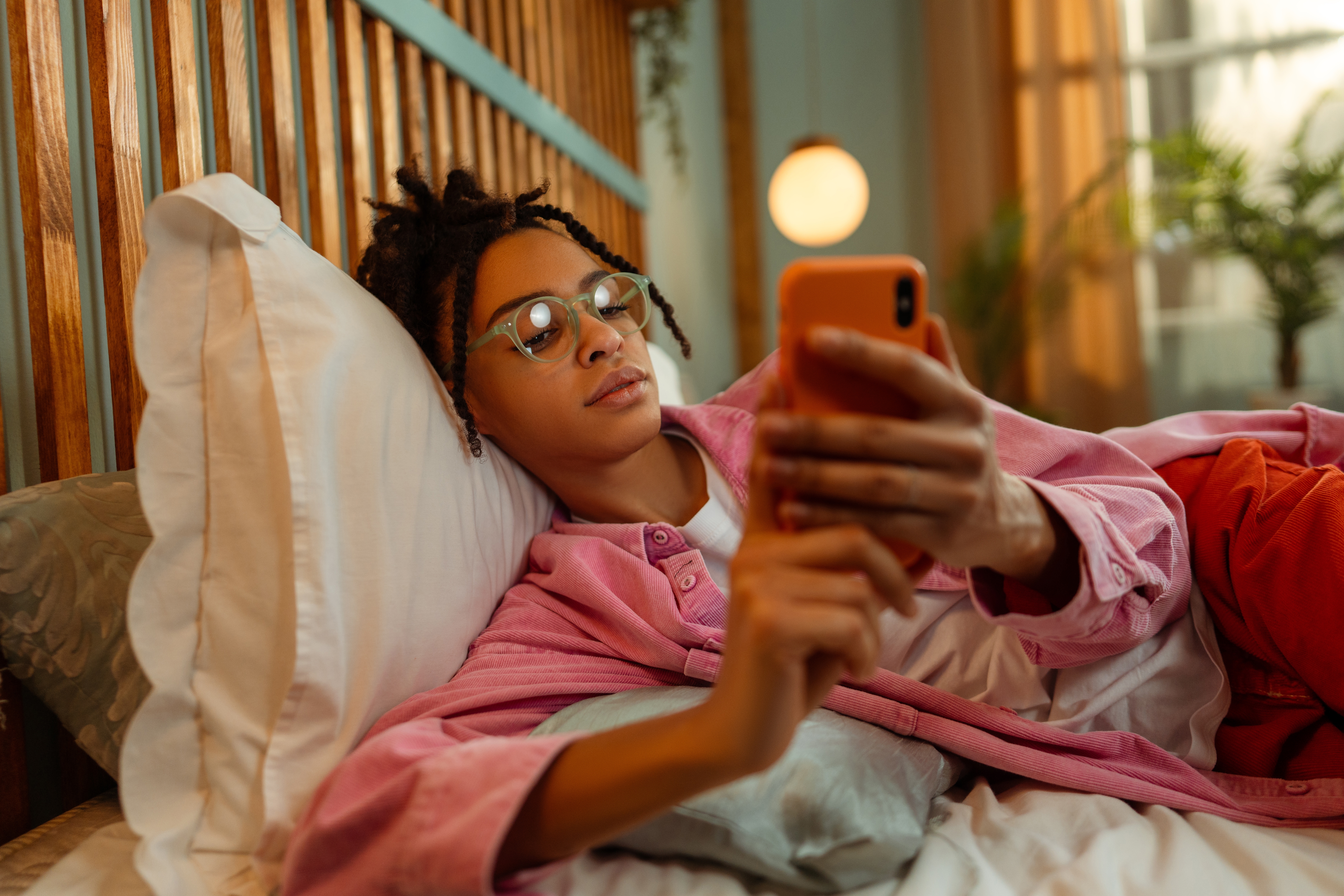 Woman on her phone learning Spanish in her bed