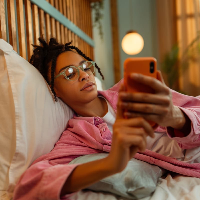 Woman on her phone learning Spanish in her bed