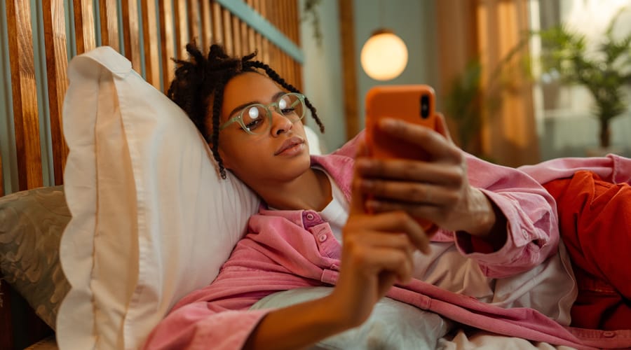 Woman on her phone learning Spanish in her bed