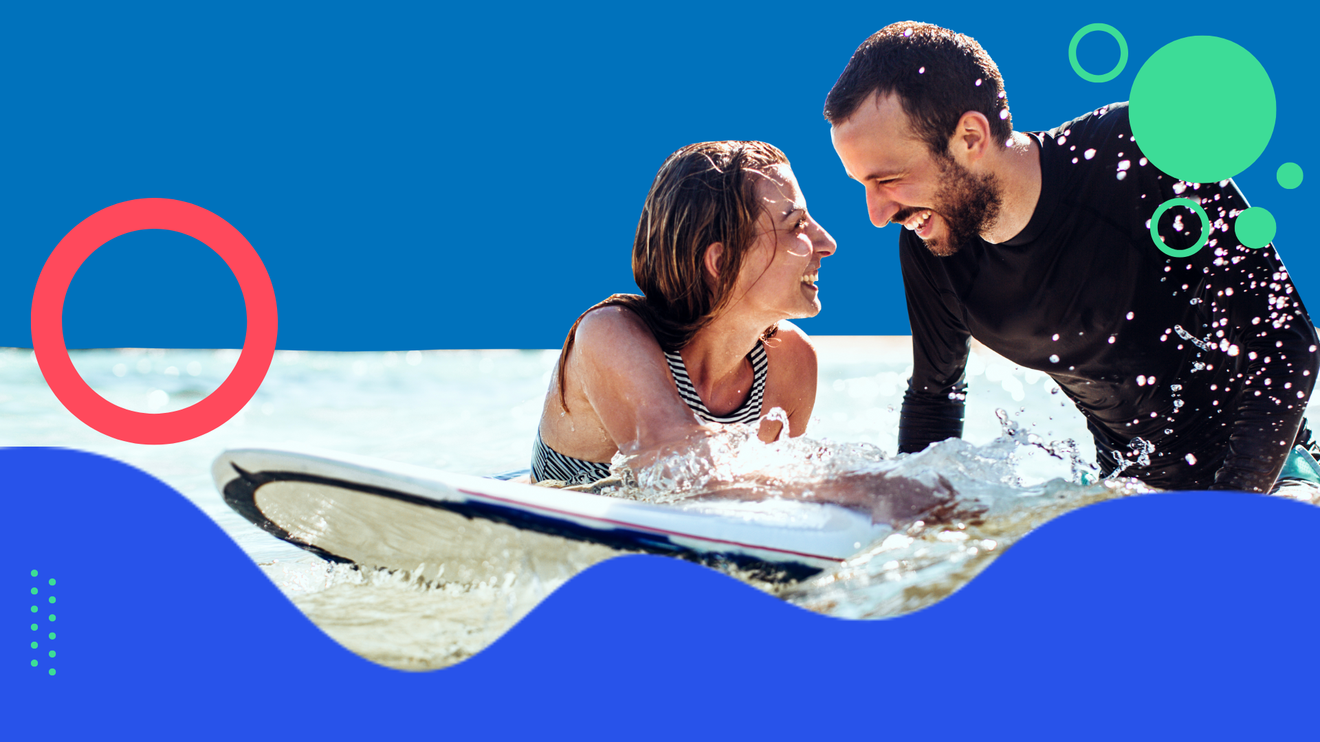 Man and woman in the water with a surf board smiling at each other